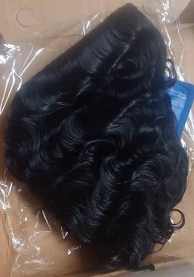 Curly black human hair wig packed in a carton